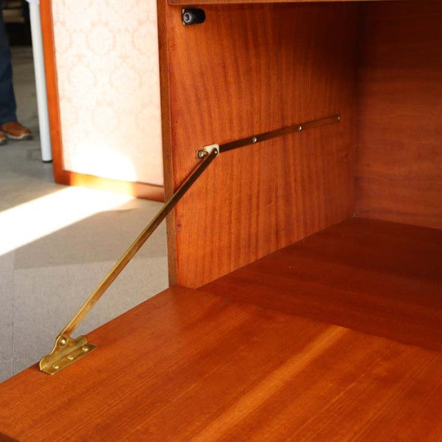 Mid-century British teak cabinet interior showing rich wood grain and brass support arm detail by Macintosh.