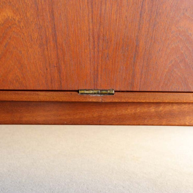 Mid-century British vintage teak cabinet door with visible wood grain and brass hinge detail.