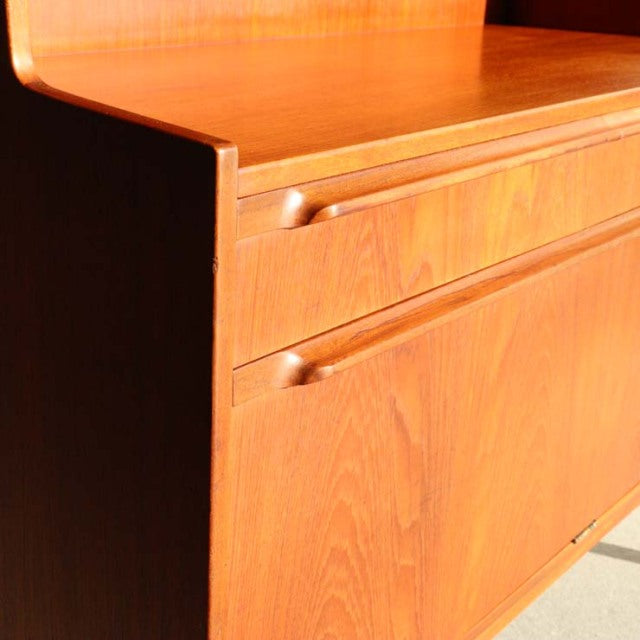 Mid-century British teak cabinet by Macintosh with smooth wood grain, sleek drawer handles, and clean lines.