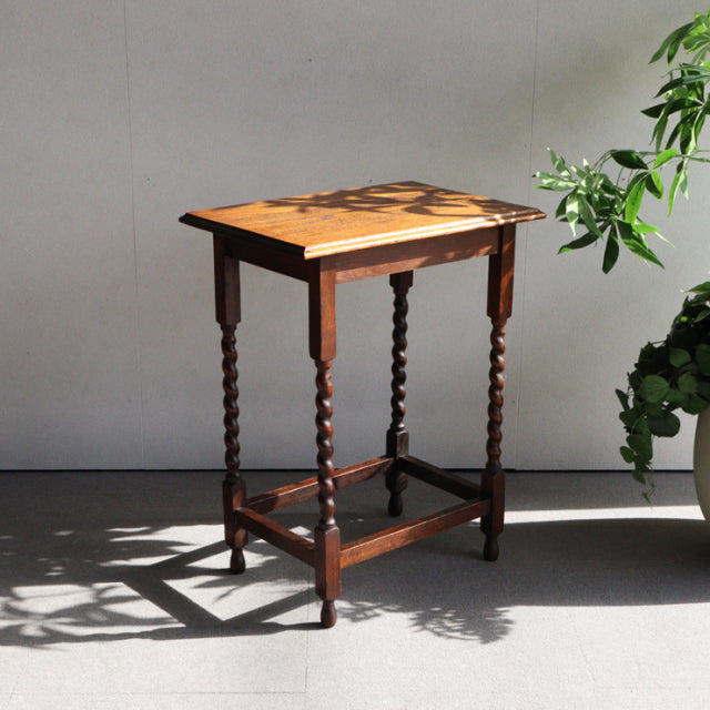 Vintage teak British mid-century side table with twisted legs, rich wood grain, and rectangular top.