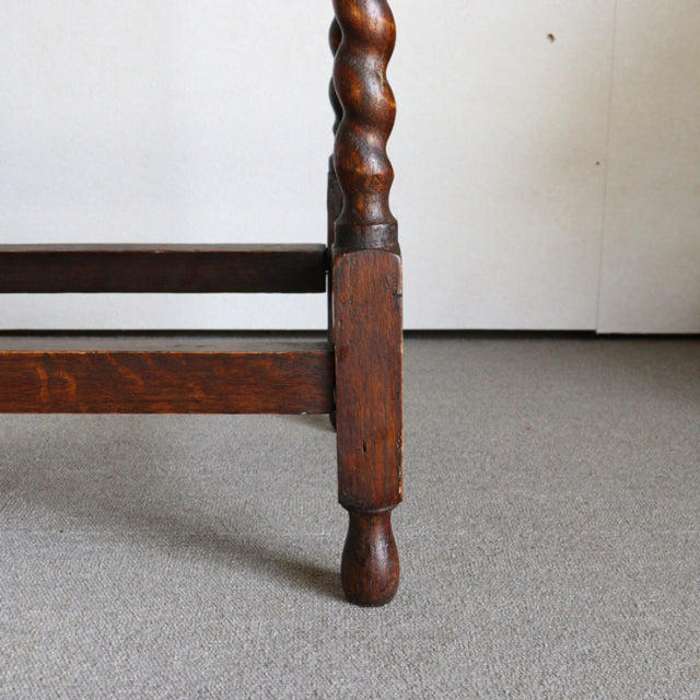 Detailed close-up of vintage teak British side table leg with twisted mid-century design and rich wood grain finish.