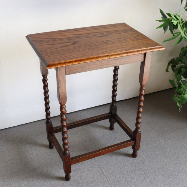 Vintage British oak side table with rich teak grain, twisted mid-century turned legs, and cross stretcher supports.