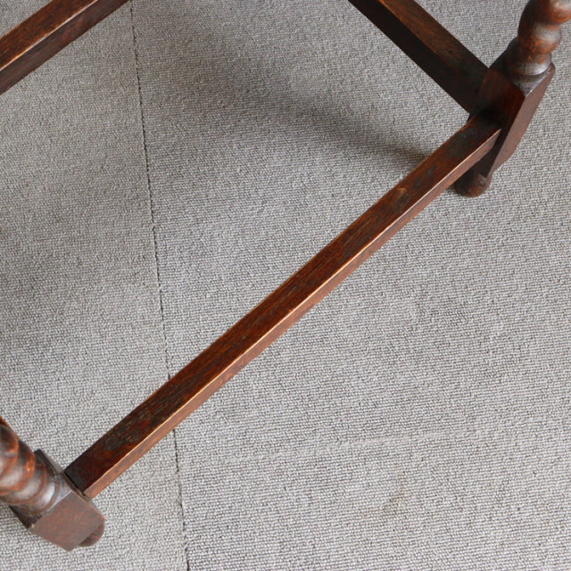 Close-up of teak wood grain and stretcher on vintage British mid-century side table with turned legs.