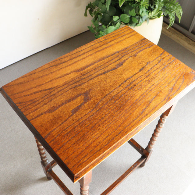 Mid-century British vintage teak side table with rich wood grain, square top, and turned legs.