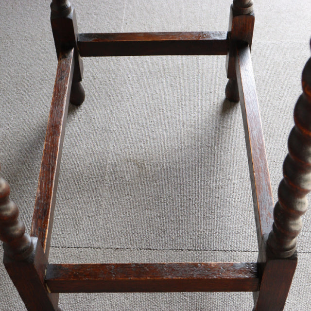 Vintage British teak side table frame with rich wood grain and twisted mid-century legs on neutral carpet.