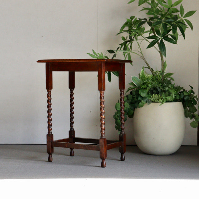 Vintage British mid-century teak side table with twisted spindle legs and rich wood grain finish, compact design.