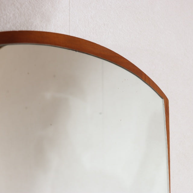 Vintage mid-century teak wall mirror from Denmark with an elegant arched top and smooth wood grain finish.