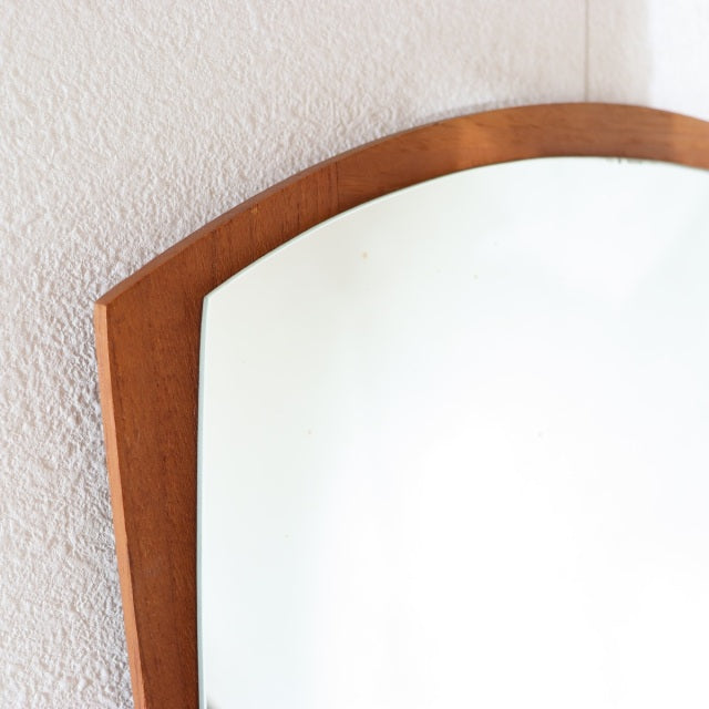Vintage mid-century Danish teak wall mirror with arched top and smooth wood grain, reflecting Scandinavian design.