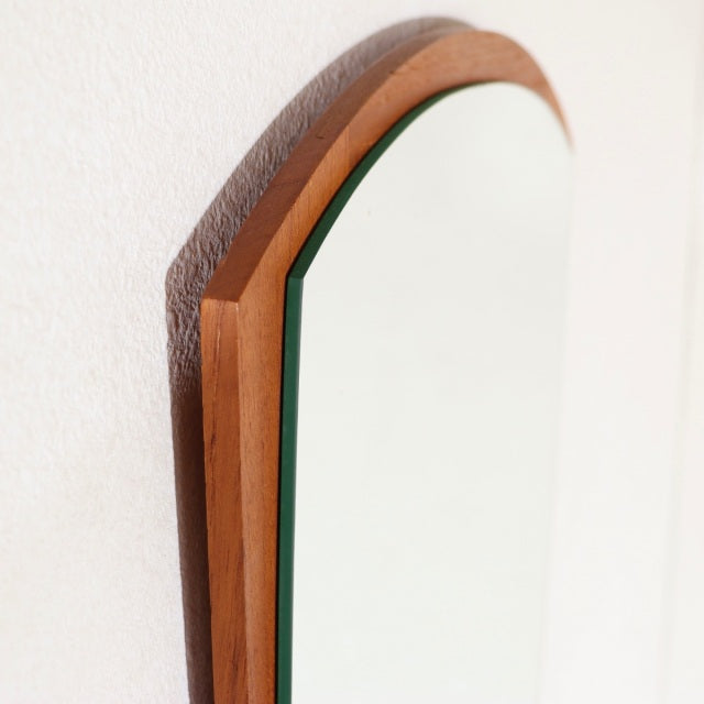 Vintage mid-century Danish teak wall mirror with smooth arch-shaped frame and visible warm wood grain detail.