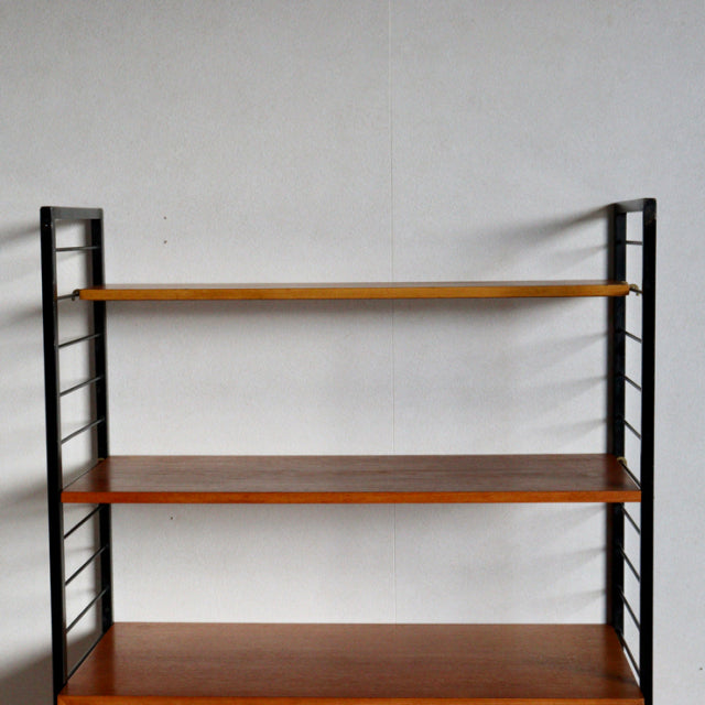Mid-century British Ladderax shelving unit with vintage teak shelves and black iron ladder frame.
