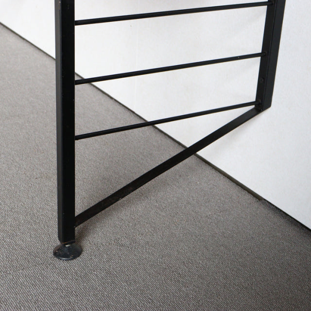 Black metal frame base with angled supports and round adjustable feet, mid-century British Ladderax shelving unit detail.