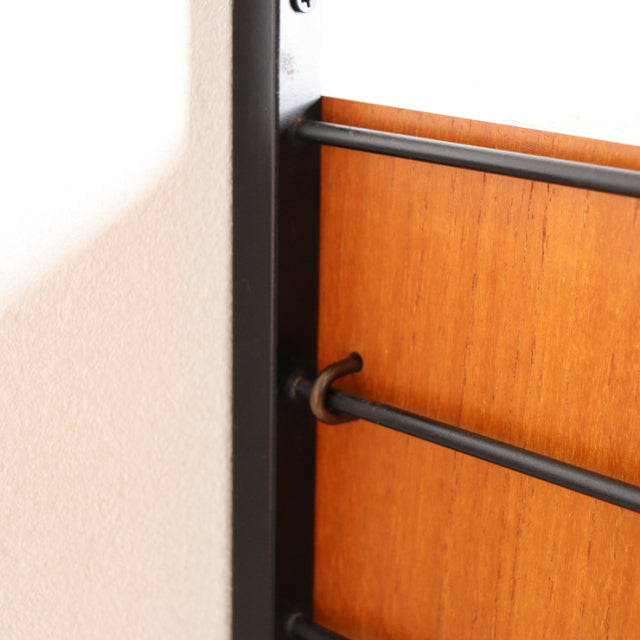 Close-up of vintage mid-century Ladderax unit shelf by Staples, featuring teak wood panel with rich grain and black metal.