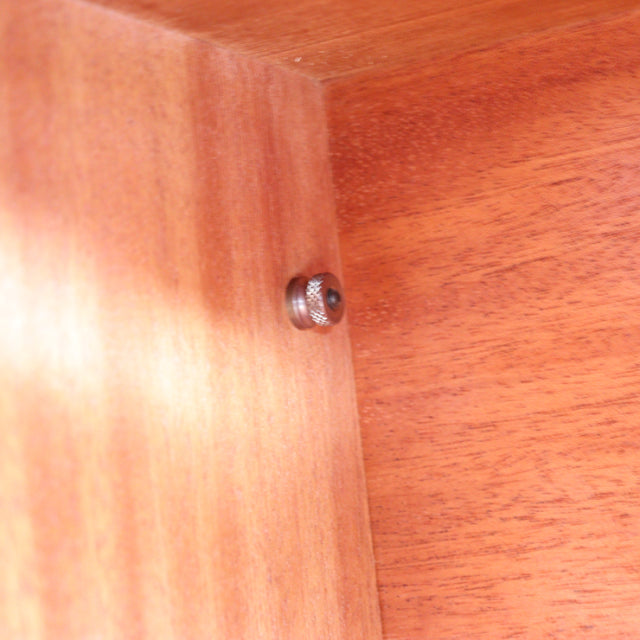 Close-up of vintage teak wood showcasing smooth grain and a metal fastening, highlighting British mid-century craftsmanship.