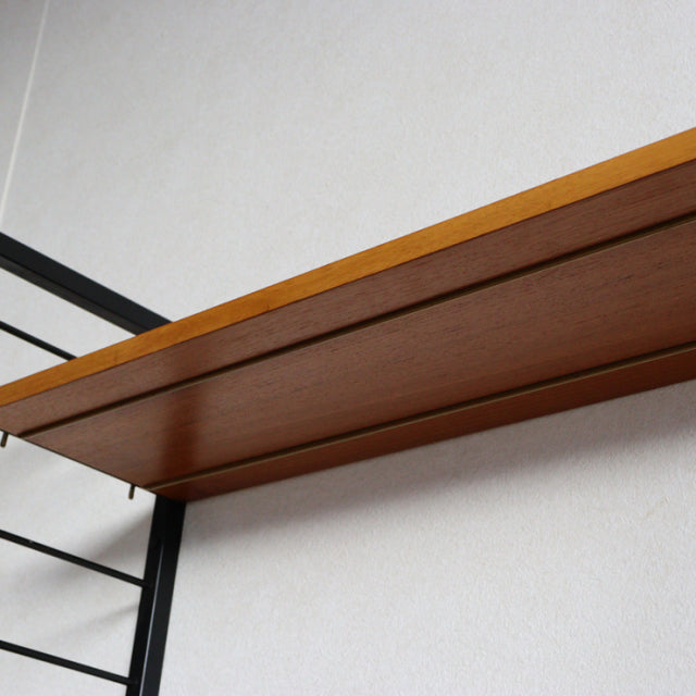 Vintage teak wood shelf unit with rich wood grain and sleek black metal ladder frame from British mid-century Ladderax system.