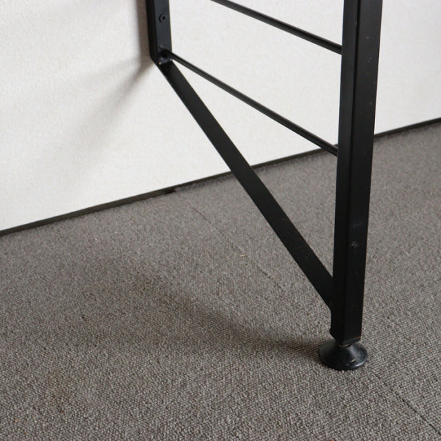 Black metal ladder frame leg with round foot and cross braces, vintage British mid-century Ladderax shelving unit detail.