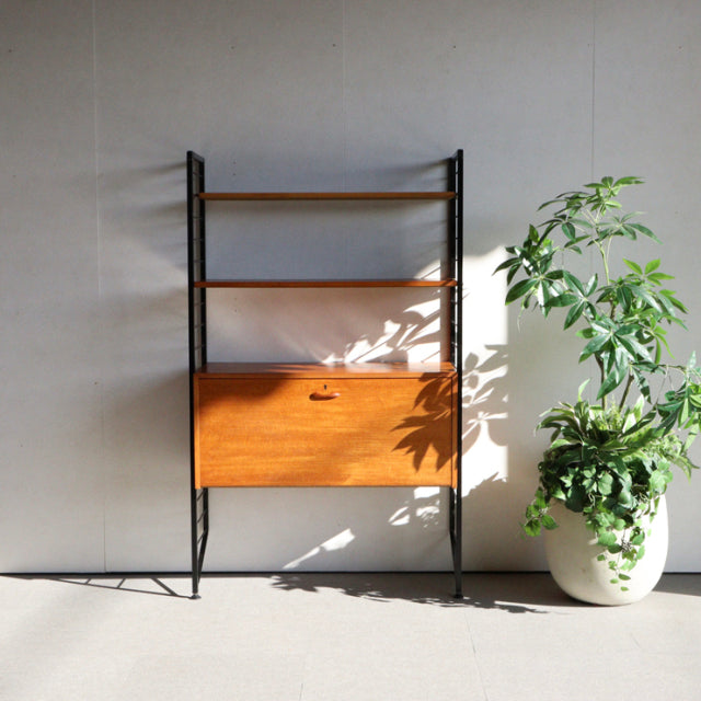 Mid-century British Ladderax unit shelf with teak drop-front cabinet, black metal frame, visible wood grain and slender.