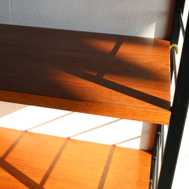 Mid-century British Ladderax shelving unit with teak wood shelves and black iron frame showing rich wood grain.