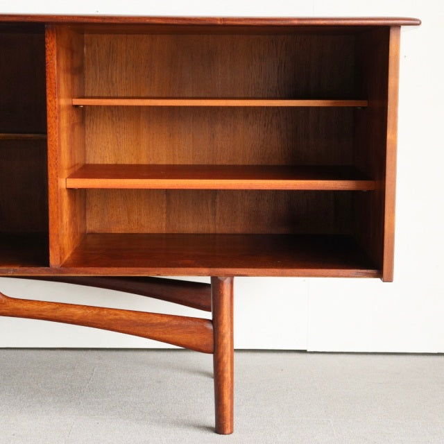 Mid-century British teak sideboard by Dalescraft with rich wood grain, open shelving, and slender tapered legs from Denmark.
