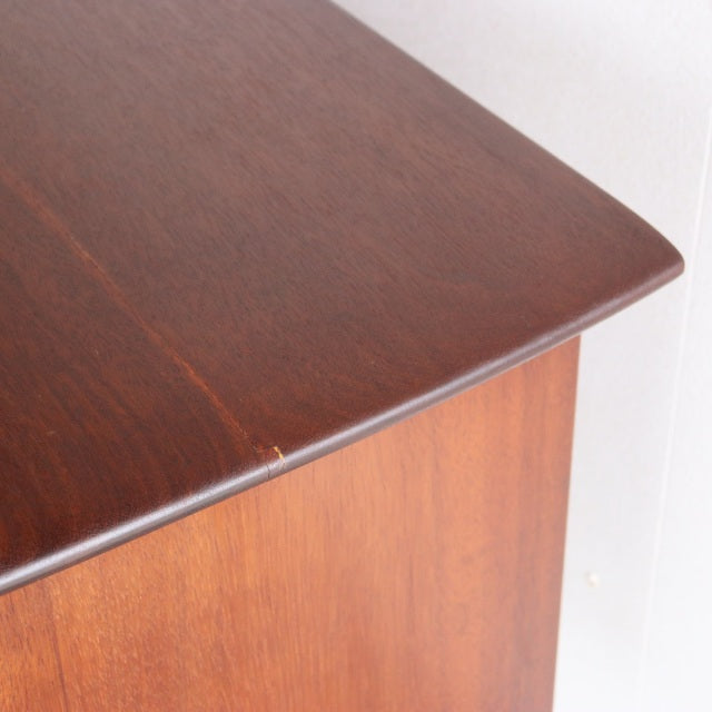 Mid-century British teak sideboard corner with rich wood grain and smooth rounded edges.