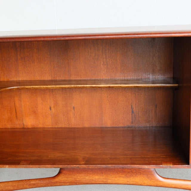 Mid-century British teak Dalescraft sideboard interior showing rich wood grain and a single shelf with smooth, warm-toned.