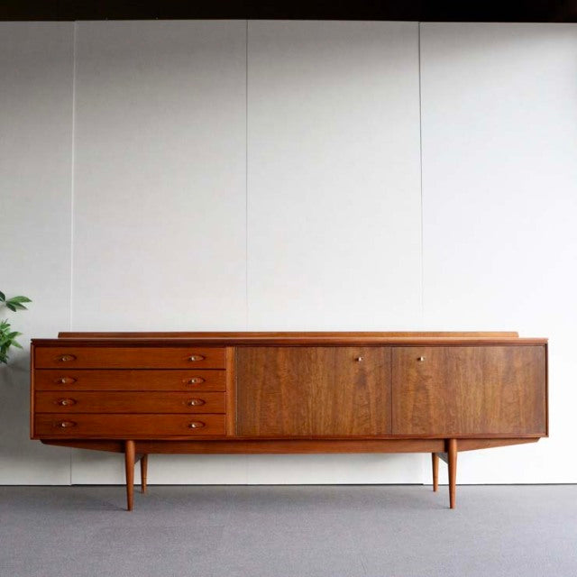 Mid-century British teak sideboard by Robert Heritage with rich wood grain, four drawers on left, sliding doors on right,.