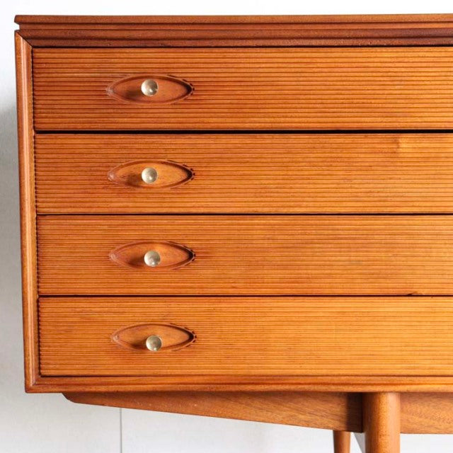 Mid-century British vintage teak sideboard drawers with distinct horizontal wood grain and oval brass handles.