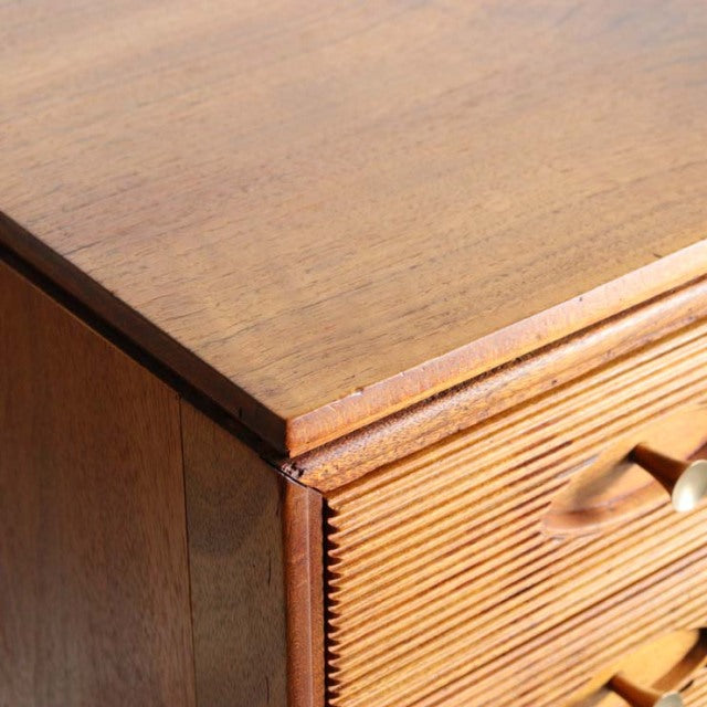 Vintage teak mid-century British sideboard corner with rich wood grain and carved drawer handles.