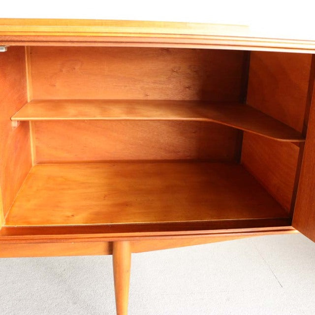 Mid-century British teak sideboard interior with adjustable shelf, showcasing warm wood grain and tapered legs from Denmark.