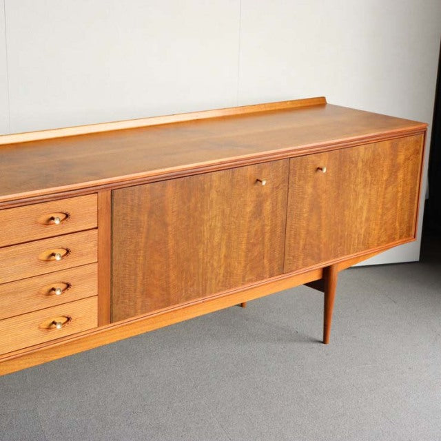 Mid-century British vintage teak sideboard by Robert Heritage with smooth wood grain, tapered legs, and brass drawer handles.