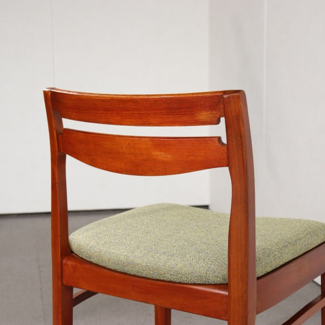 Mid-century British vintage teak dining chair by NATHAN with curved wooden backrest and green upholstered seat cushion.