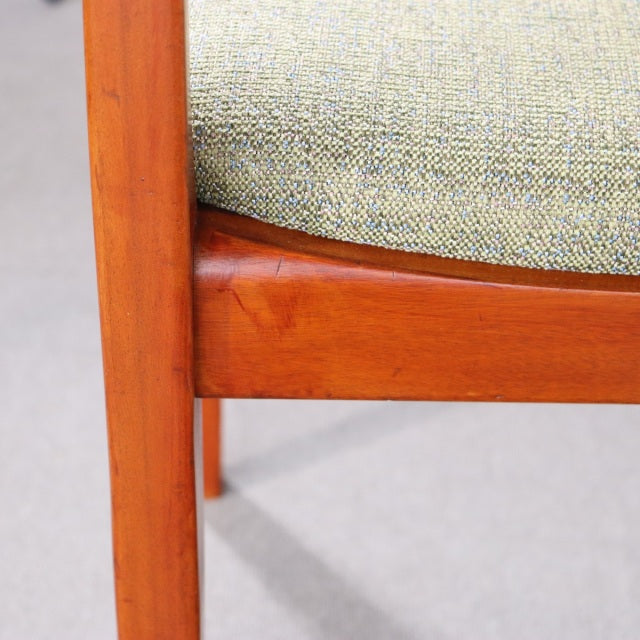 Vintage teak dining chair leg and frame with visible wood grain and mid-century Danish design upholstered in textured fabric.