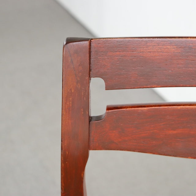 Close-up of vintage British mid-century teak dining chair backrest with smooth curved slats and visible wood grain.