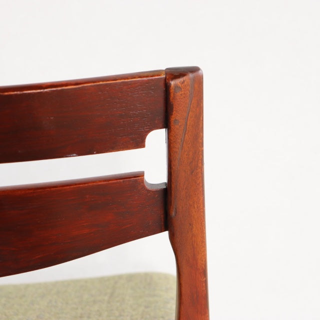 Close-up of vintage mid-century teak dining chair backrest with visible wood grain and British design influences.