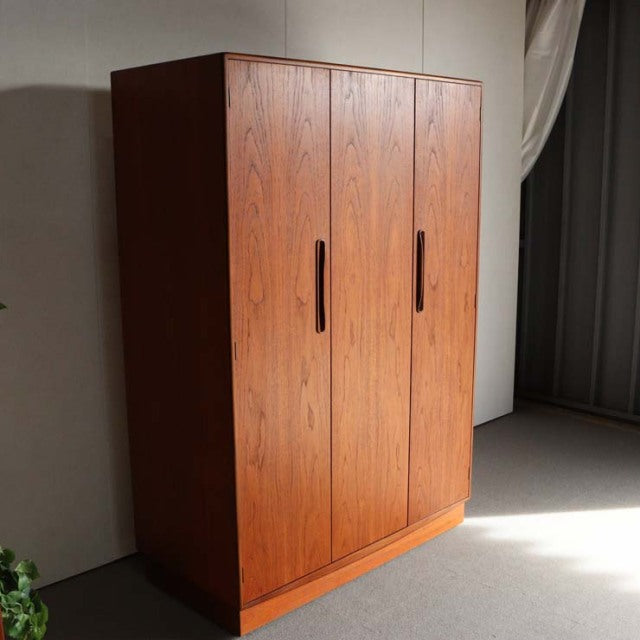 Vintage British mid-century G-Plan teak wardrobe with rich wood grain, three doors, and sleek vertical handles.