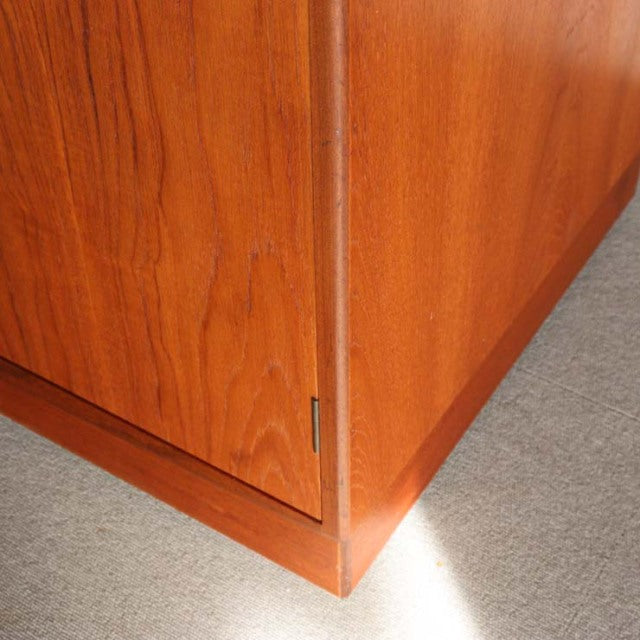Corner detail of vintage British mid-century teak G-Plan wardrobe with smooth wood grain and clean lines on carpeted floor.