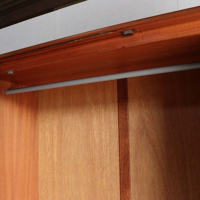 Close-up of vintage British mid-century teak wardrobe interior showing smooth wood grain and metal hanging rod with Danish.
