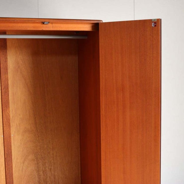 Vintage mid-century teak wardrobe by G-Plan, British design with clean lines and warm wood grain, open door showing spacious .