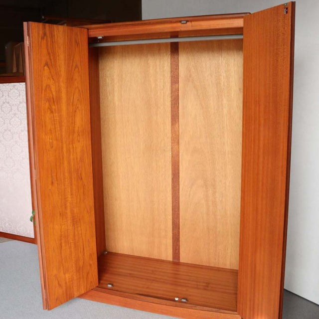 Open vintage British mid-century G-Plan teak wardrobe with visible wood grain and hanging rail inside.
