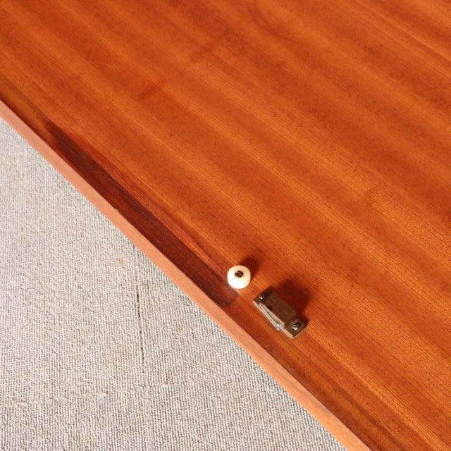 Close-up of British mid-century G-Plan wardrobe door in warm teak with visible wood grain and brass lock detail, showcasing.