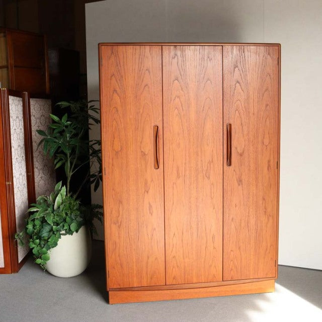 Vintage mid-century G-Plan teak wardrobe with visible wood grain, sleek vertical handles, and British design, standing on a.