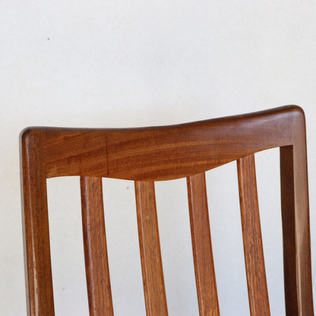 Mid-century British G-Plan dining chair in teak with curved slatted backrest showing rich wood grain.