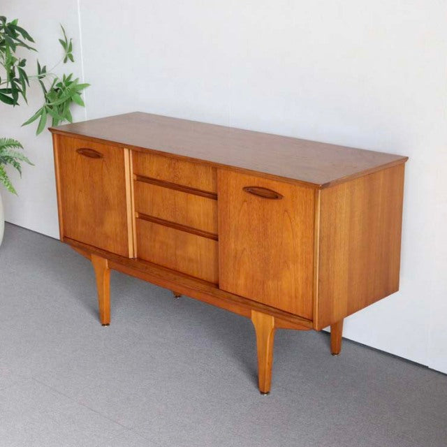 Compact British mid-century teak sideboard by Jentique with rich wood grain, tapered legs, and minimalist handles.