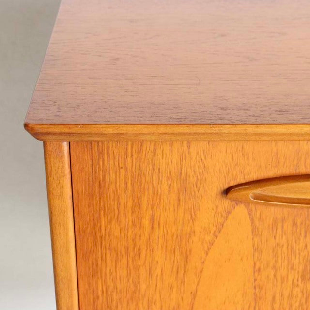 Close-up of vintage British mid-century teak sideboard corner showing smooth wood grain and rounded edge detail.