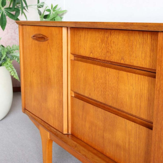 Compact Jentique vintage teak sideboard with smooth wood grain, mid-century British design, tapered legs, and Danish.