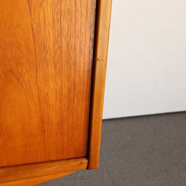 Close-up of vintage teak wood grain and corner detail on British Jentique mid-century Denmark sideboard leg.