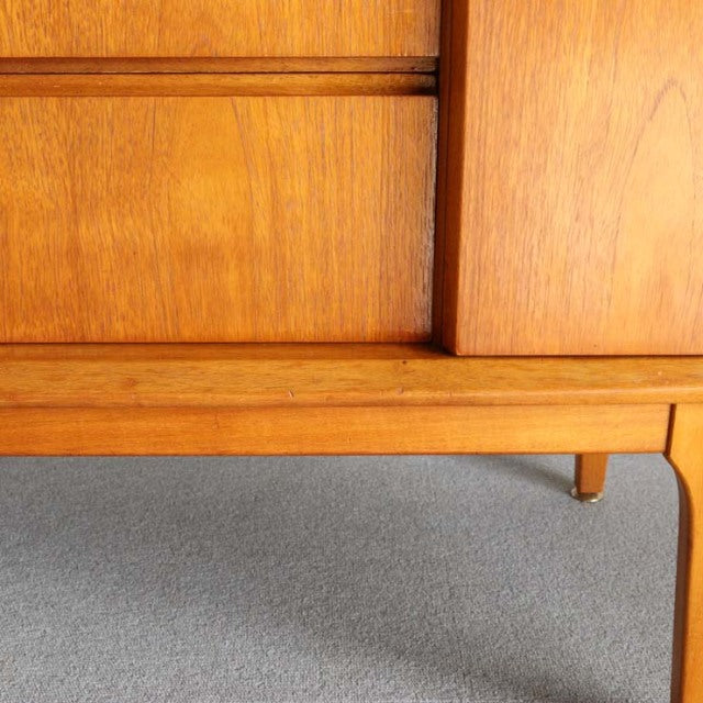 Close-up of vintage British mid-century teak sideboard by Jentique with smooth wood grain and tapered legs, showcasing.