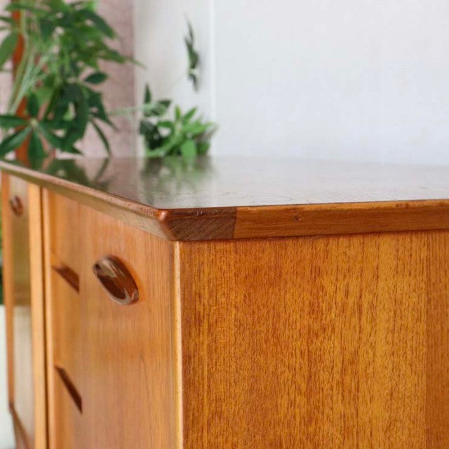 Compact vintage teak sideboard by Jentique with rich wood grain, mid-century British design, slender legs, and smooth.