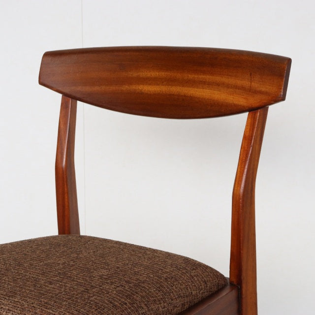 Mid-century British McIntosh dining chair in vintage teak with curved wood grain backrest and brown fabric seat.
