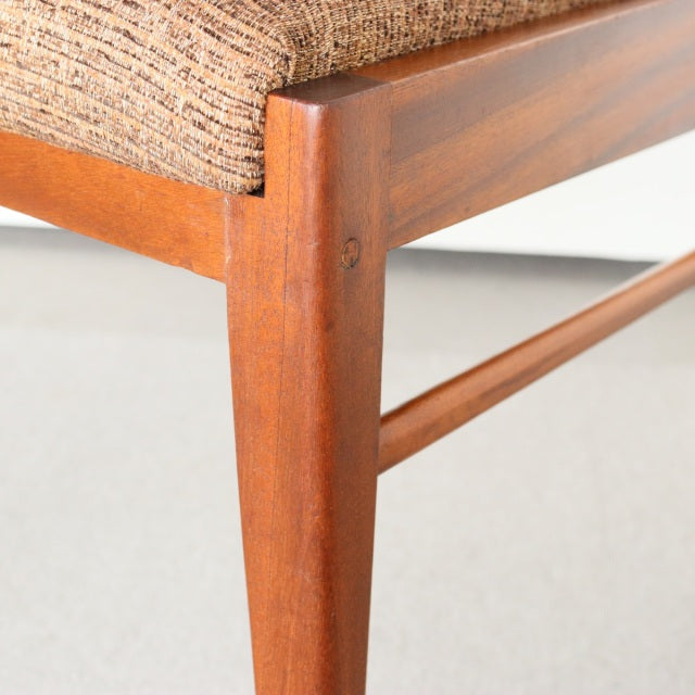 Vintage McIntosh British mid-century teak dining chair leg with smooth wood grain and fabric seat corner.