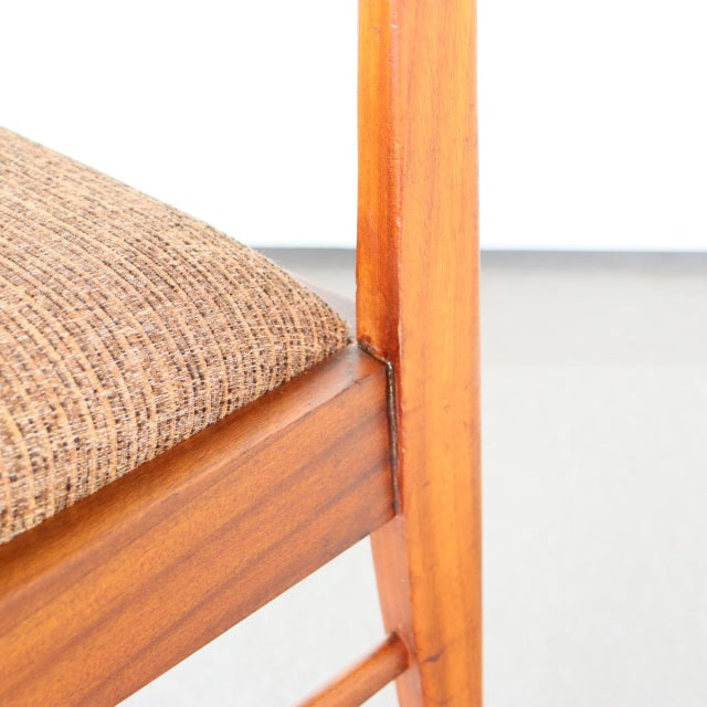 Mid-century British McIntosh teak dining chair leg and textured brown fabric seat corner close-up showcasing wood grain and.